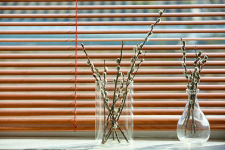Vases with willow branches on windowsill in roomの写真素材