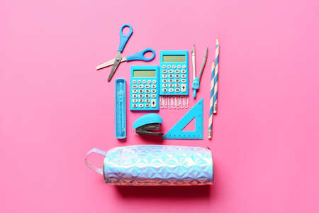 Pencil case with stationery and calculators on color backgroundの写真素材