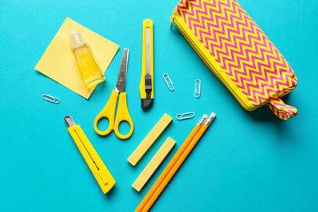 Pencil case with stationery and bottle of sanitizer on color background