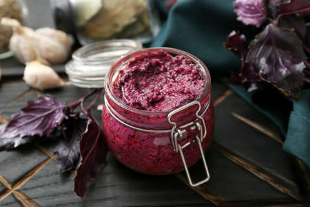 Wooden board with jar of tasty pesto sauce on table, closeupの写真素材