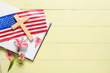 Book with cross, flowers and USA flag on yellow wooden backgroundの写真素材