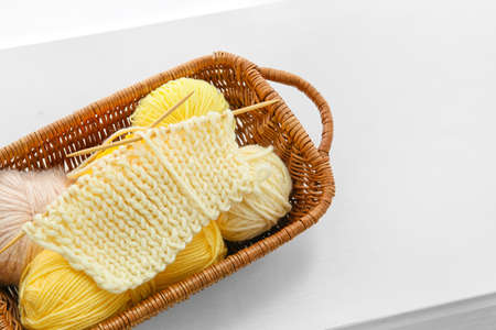 Wicker basket with knitting yarn and needles on tableの写真素材