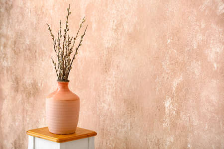 Vase with willow branches on table near color wallの写真素材