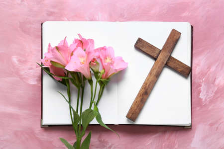 Book with lily flowers and wooden cross on pink backgroundの写真素材