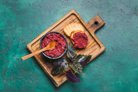 Wooden board with bowl of pesto sauce and toasts on color backgroundの写真素材