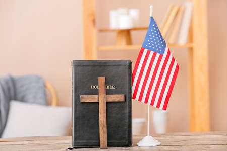 Holy Bible with cross and USA flag on table in roomの写真素材