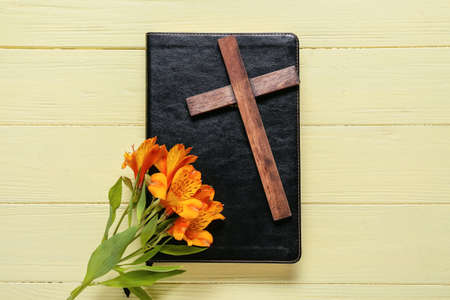 Book with cross and lily flowers on yellow wooden backgroundの写真素材