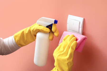 Woman cleaning switch on pink wall, closeupの写真素材