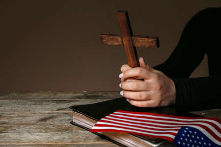Woman with cross, Holy Bible and USA flag on dark wooden backgroundの写真素材