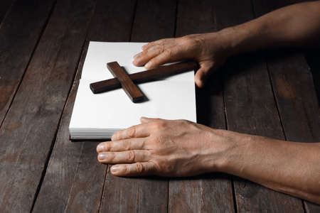 Man with cross and Holy Bible on dark wooden backgroundの写真素材