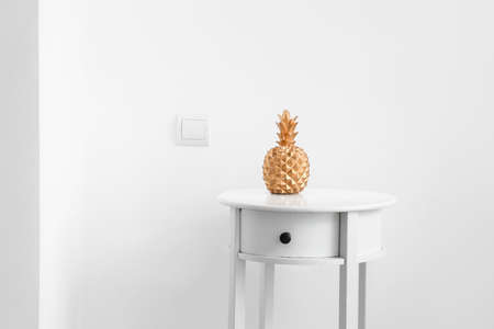 Table with decorative pineapple near white wallの写真素材