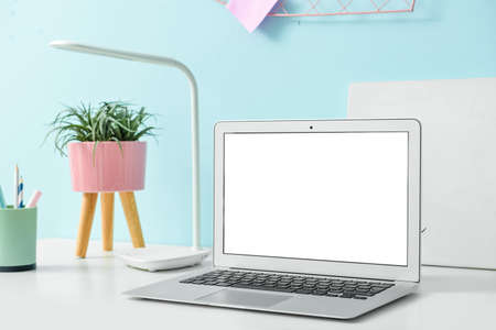 Comfortable workplace with modern laptop on table near color wallの写真素材