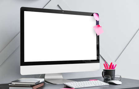 Comfortable workplace with modern PC monitor on table near light wallの写真素材