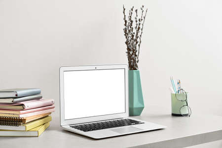 Comfortable workplace with laptop and notebooks near light wallの写真素材