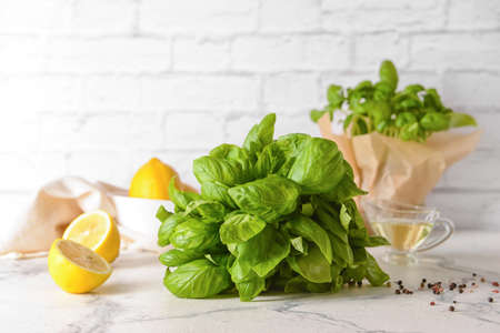 Composition with fresh basil and lemons on table against brick wallの写真素材