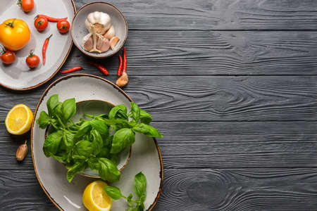 Composition with fresh basil leaves and different products on dark wooden backgroundの写真素材