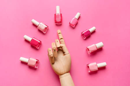 Bottles of nail polishes and wooden hand on color backgroundの写真素材