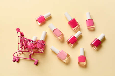 Shopping cart with nail polishes on color backgroundの写真素材