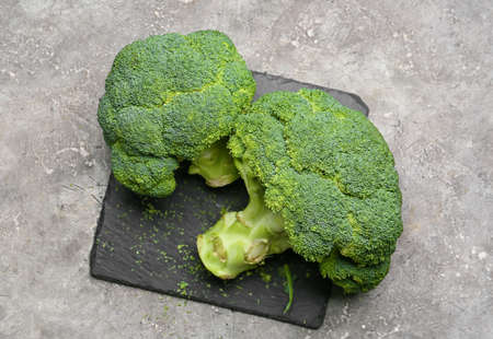 Board with healthy broccoli cabbages on gray backgroundの写真素材