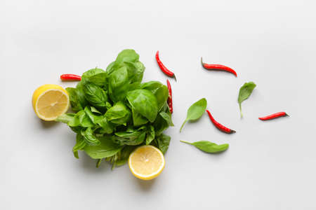 Fresh basil leaves, lemon and chili peppers on light backgroundの写真素材