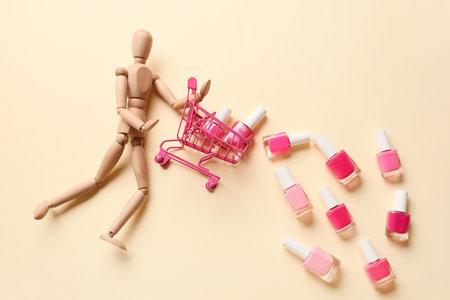 Wooden mannequin with shopping cart and nail polishes on color backgroundの写真素材