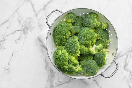 Colander with healthy broccoli cabbage on light backgroundの写真素材