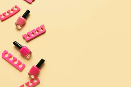 Bottles of nail polishes and toe dividers on color backgroundの写真素材