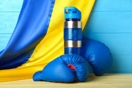 Boxing gloves, bottle for water and flag of Ukraine on color wooden backgroundの写真素材