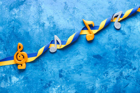 Music notes and ribbon in colors of Ukrainian flag on color backgroundの写真素材