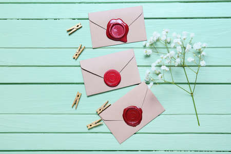 Envelopes with clothespins and flowers on green wooden background