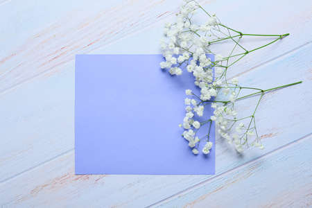 Blank card with flowers on white wooden background