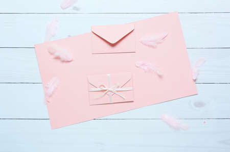 Blank card with envelopes and feathers on white wooden backgroundの写真素材