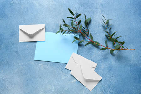 Blank card with envelopes and plant branch on blue backgroundの写真素材