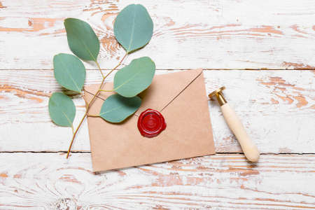 Envelope with plant branch and stamp on white wooden background