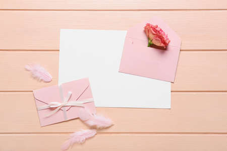 Blank card with envelopes, rose and feathers on pink wooden backgroundの写真素材