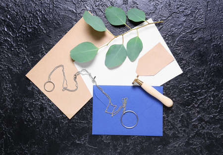 Cards with envelope, stamp, plant branch and jewelry on black background
