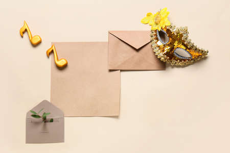 Blank card with envelopes and carnival mask on beige background