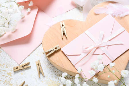 Envelopes with flowers and clothes pins on white background