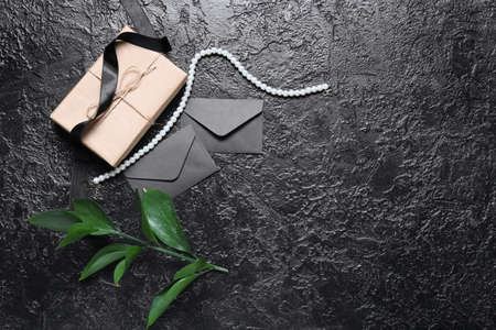 Envelopes with ribbon, necklace and plant branch on black backgroundの写真素材