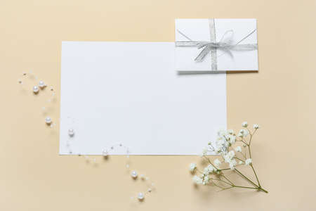 Blank card with envelope and flowers on beige backgroundの写真素材
