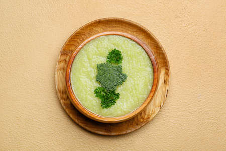 Bowl of tasty broccoli cream soup on color background