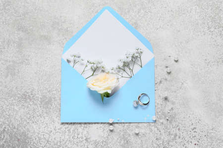 Envelope with flowers and ring on light background