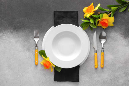 Beautiful table setting with narcissus flowers on black and white backgroundの写真素材