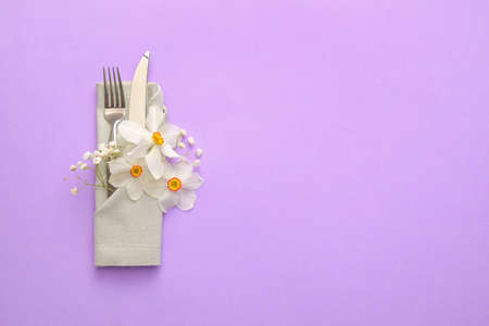 Beautiful table setting with narcissus flowers on color backgroundの写真素材
