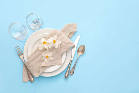 Beautiful table setting with narcissus flowers on color backgroundの写真素材