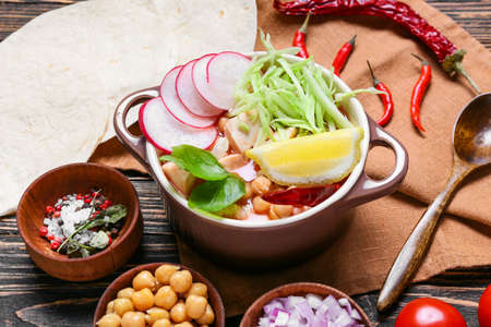 Pot with tasty pozole soup and ingredients on wooden backgroundの写真素材