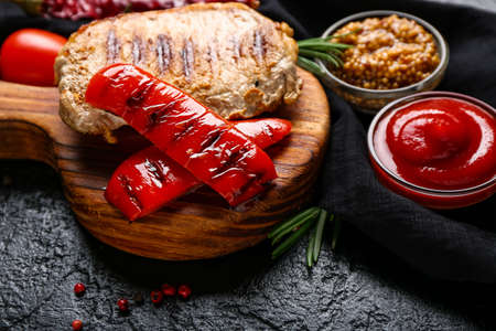 Board with tasty grilled pepper and steak on dark backgroundの写真素材