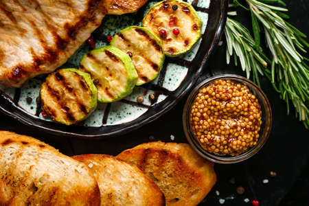 Plate with tasty grilled vegetables, steak and bread on dark backgroundの写真素材
