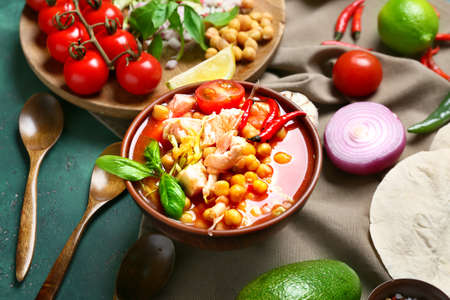 Bowl with tasty pozole soup and ingredients on green backgroundの写真素材