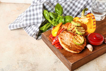 Board with tasty grilled vegetables and steaks on light backgroundの写真素材